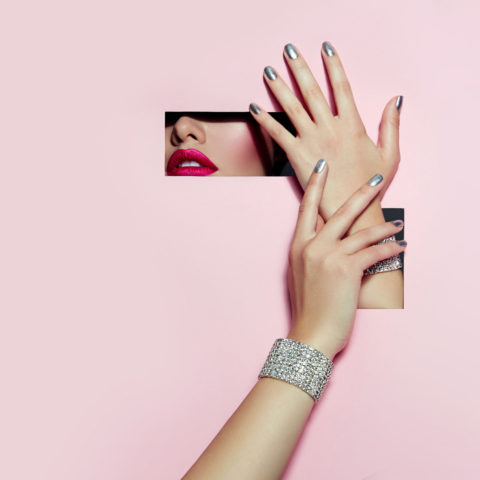 Portrait of a beautiful blue-eyed girl with bright make-up and hand covering her eyes. on his hand a massive gold ring with large colored stones.